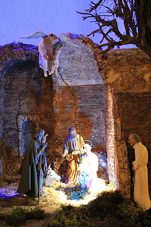 Presepe in stile romano illuminato di notte, con natività tra rovine antiche